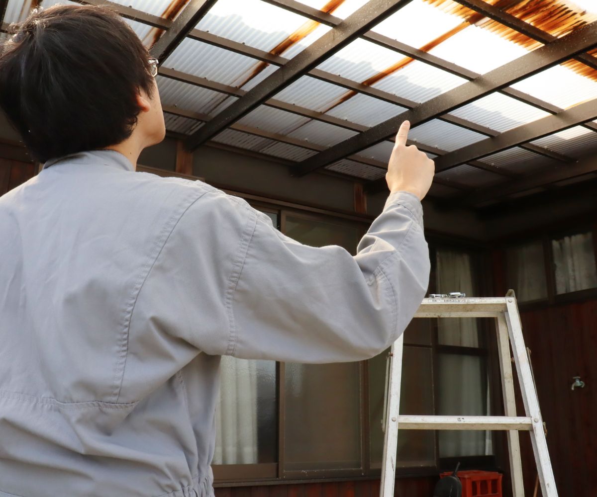 Person inspecting roof near a ladder.