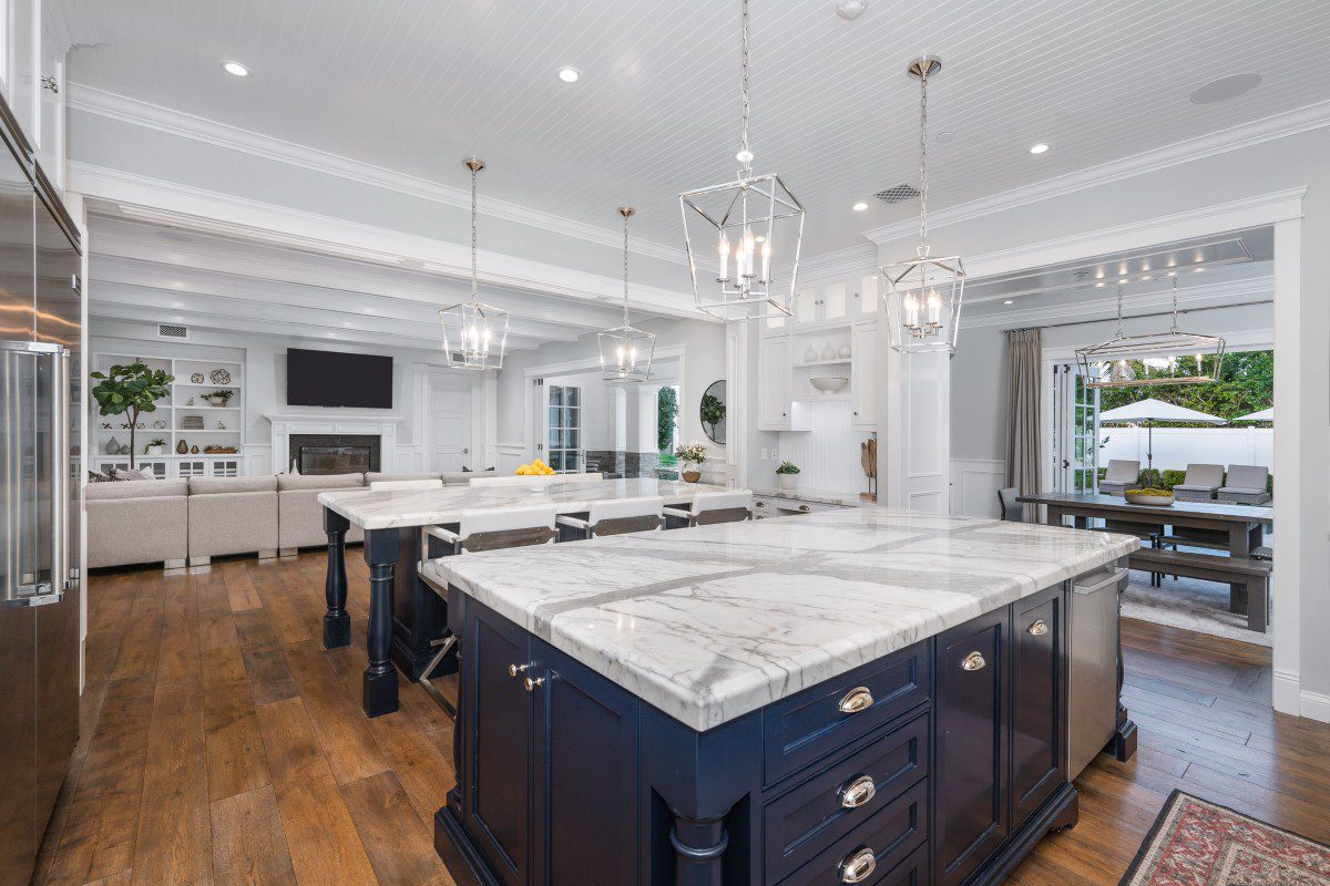 Modern kitchen with marble countertops and chandeliers.